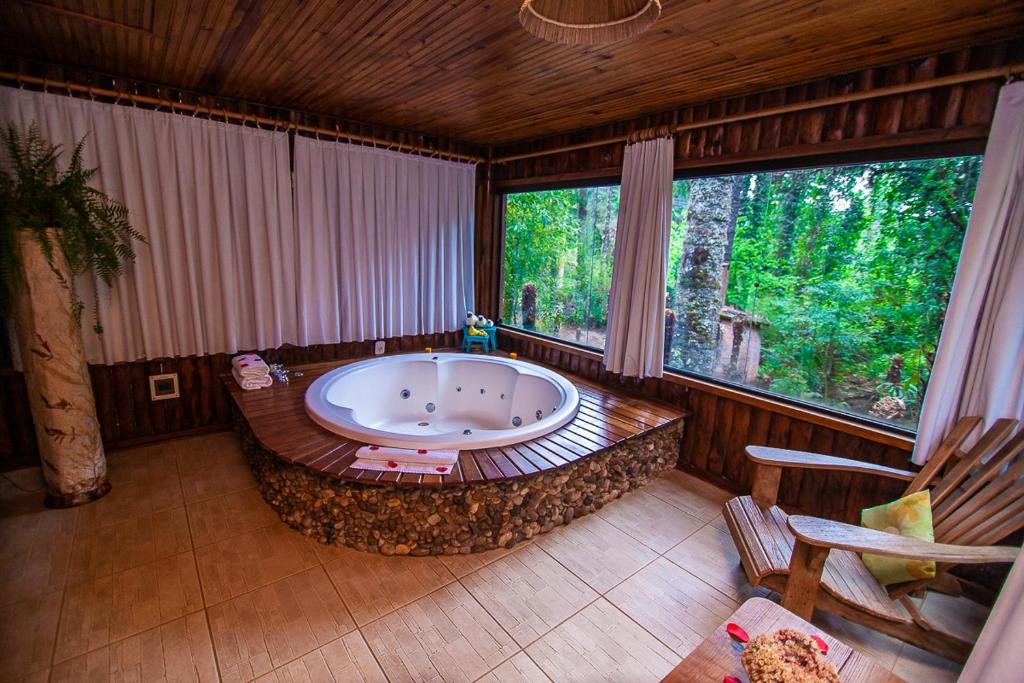 uma grande banheira num quarto com janelas em Pousada Villa D'Amore em Monte Verde