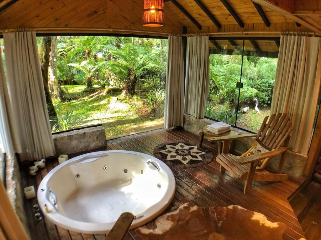 eine Badewanne in einem Zimmer mit Stuhl in der Unterkunft Pousada Villa D'Amore in Monte Verde