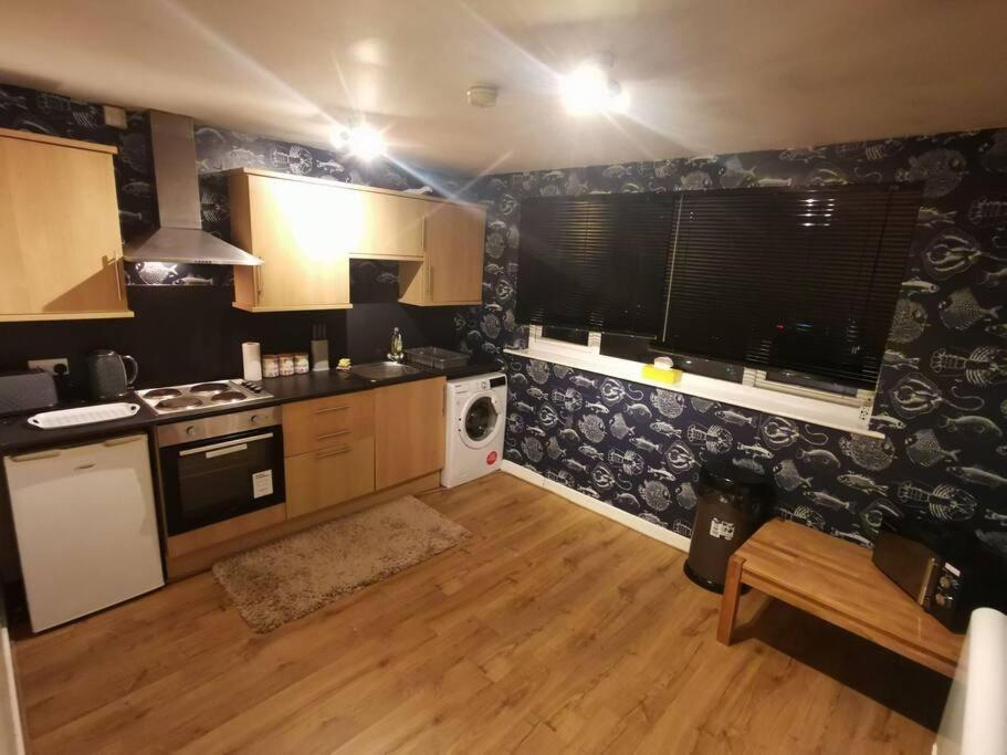 uma cozinha com paredes em preto e branco e pisos em madeira em Lovely Centralised 1Bed Apt Near Town Centre & Beach - Free Wi-Fi & Parking em Fleetwood