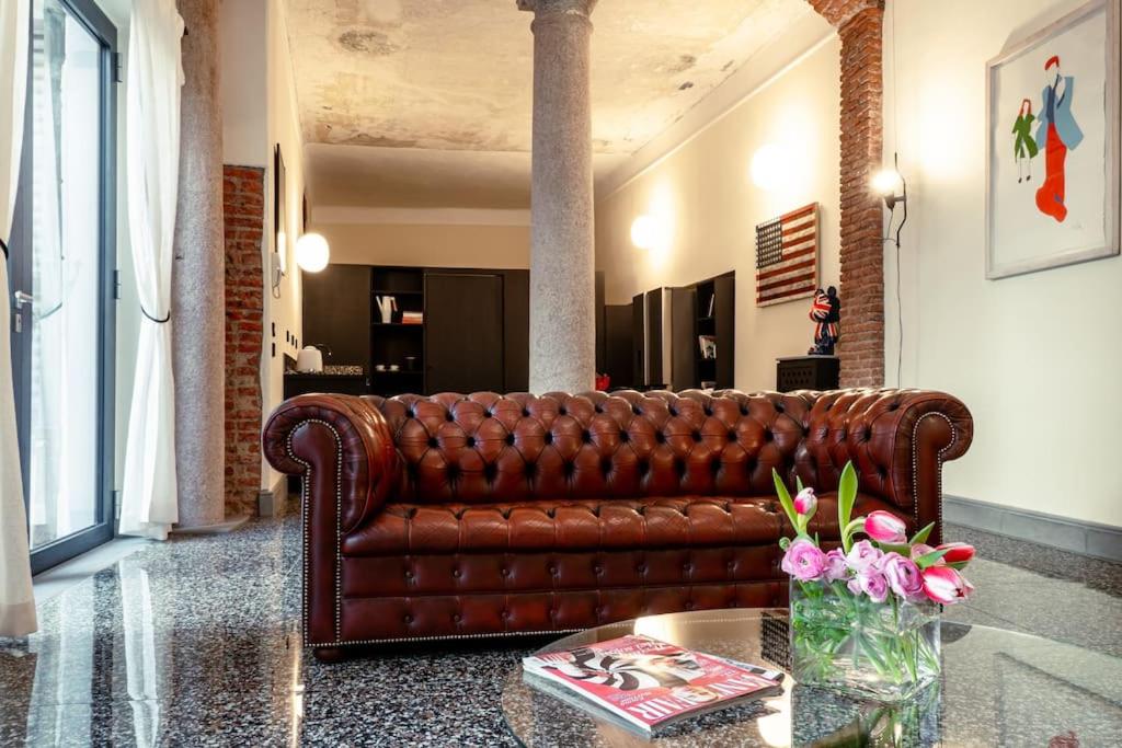 um sofá de couro castanho numa sala de estar com uma mesa em Luxury Loft near Duomo and Garage em Milão