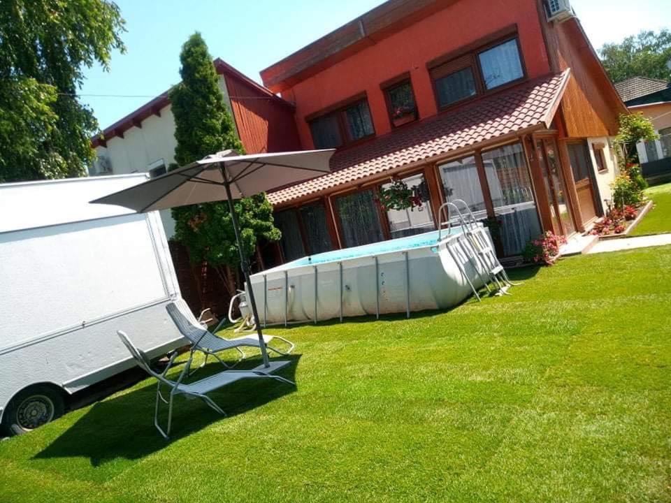einen Hof mit einem Tisch und einem Regenschirm vor einem Haus in der Unterkunft Vivien vendégház in Zamárdi