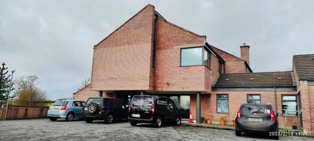 een gebouw met auto's geparkeerd op een parkeerplaats bij The Cloisters in Dingle