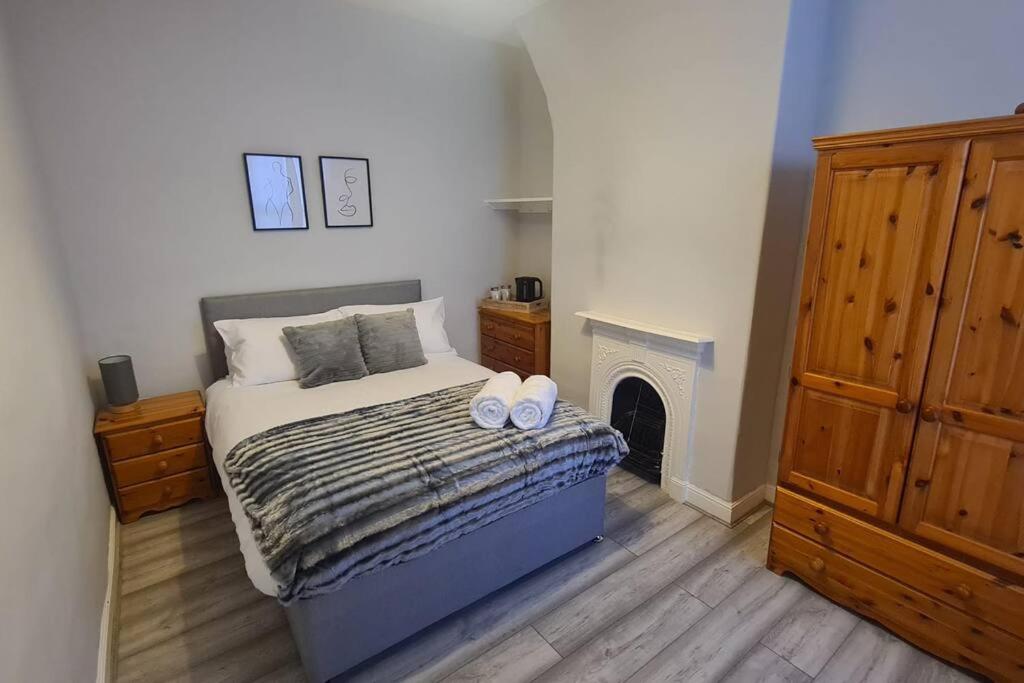 a bedroom with a bed with two pillows and a fireplace at Entire House Near City Centre with Parking Permit (3 bedrooms, Sleeps 8) in Liverpool