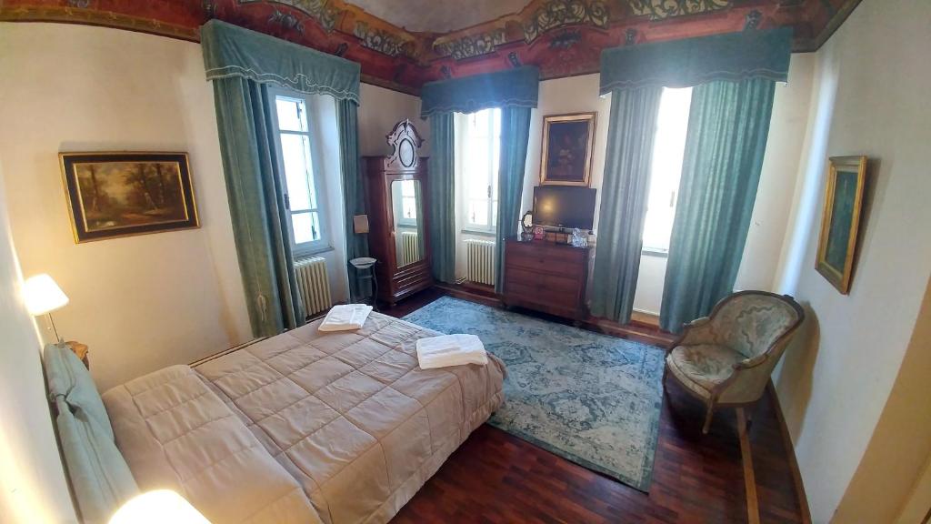 a bedroom with a bed and a chair and windows at Bresbot B&B in Bressana Bottarone