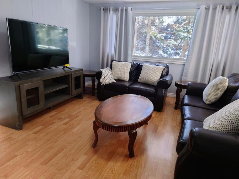 a living room with couches and a flat screen tv at Red Island Cozy Casa in Summerside