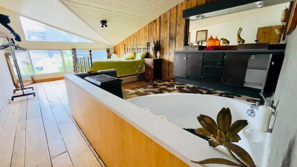 a large bathroom with a tub and a bedroom at Carwyns Surf House in Seignosse