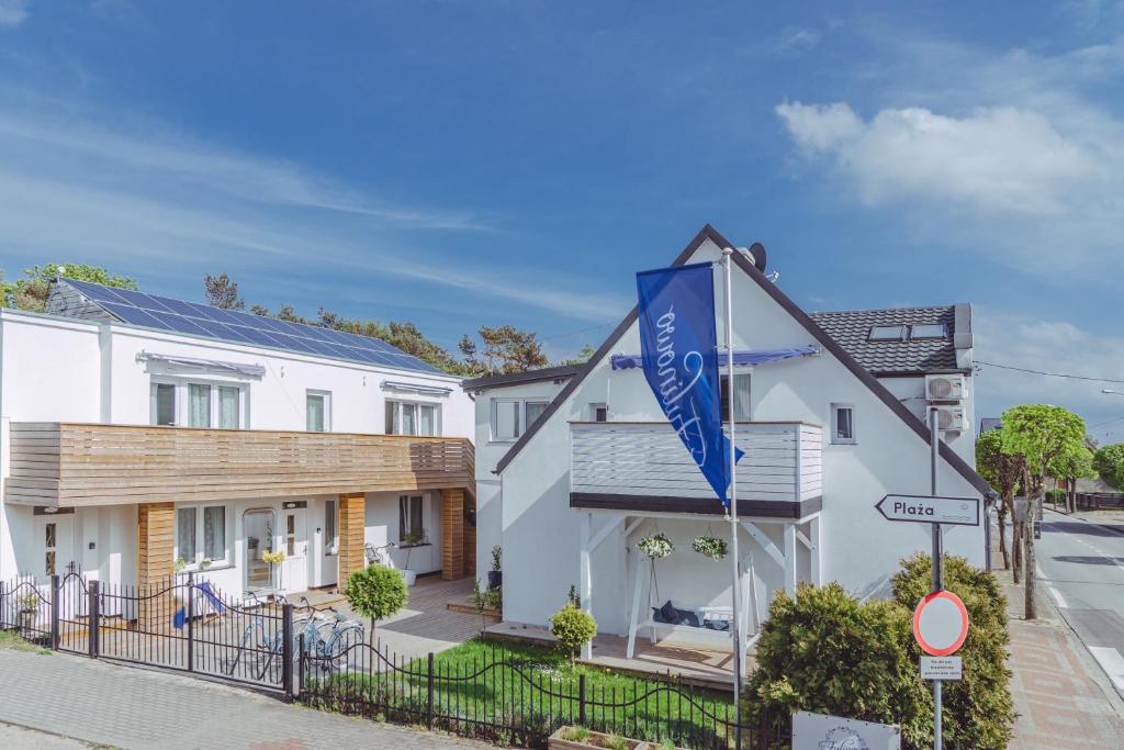 un edificio blanco con una bandera azul delante de él en Fulinowo - Kuźnica, en Kuźnica