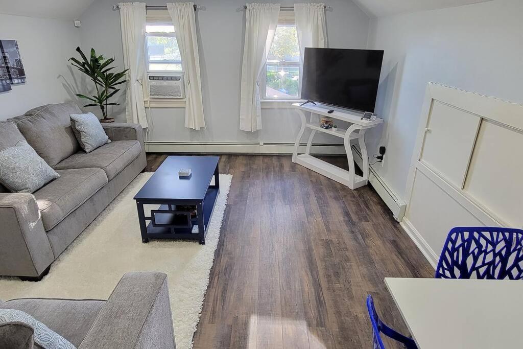 uma sala de estar com um sofá e uma televisão de ecrã plano em Cheerful 2-Bedroom Apartment with Smart Home Tech. em Uniondale