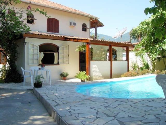 a house with a swimming pool in front of a house at Casa com 6 Suites, piscina e estacionamento in Ilhabela