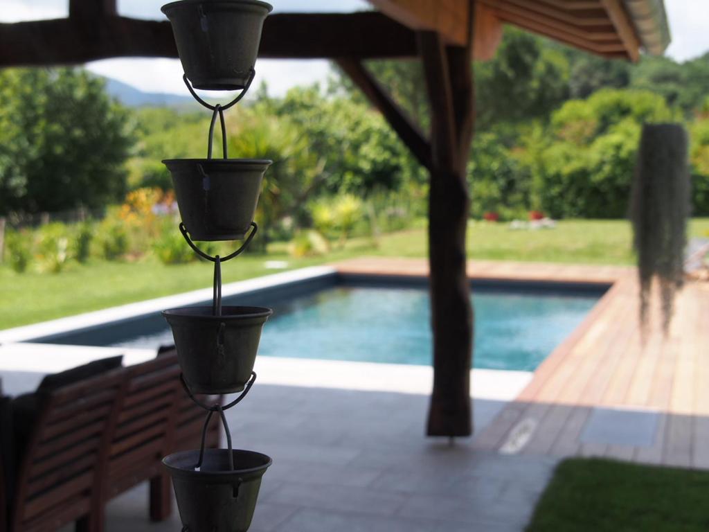a pair of hanging flower pots in front of a pool at Charmant T2 avec piscine entre mer et montagne in Ibarron