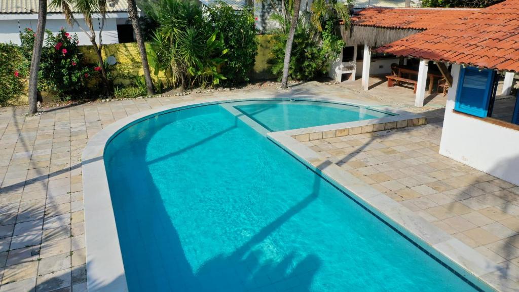 a large blue swimming pool with a red roof at Casa Bonita da Barra - 04 quartos, 170m da praia barramar in Barra de São Miguel