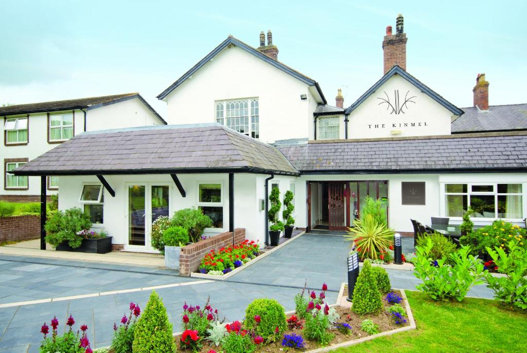 - un grand bâtiment blanc avec des fleurs dans la cour dans l'établissement The Kinmel & Kinspa, à Abergele