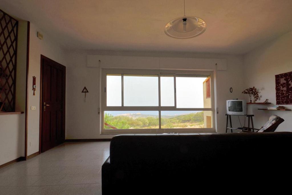 uma sala de estar com uma grande janela e um sofá em Appartamenti Salusai em Trinità d'Agultu e Vignola