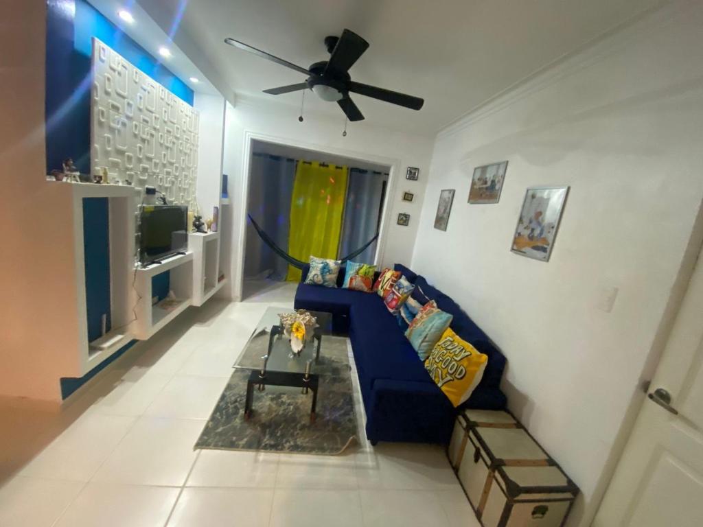 ein Wohnzimmer mit einem blauen Sofa und einem Deckenventilator in der Unterkunft Hermoso Apartamento Carmen Renata III in Pantoja
