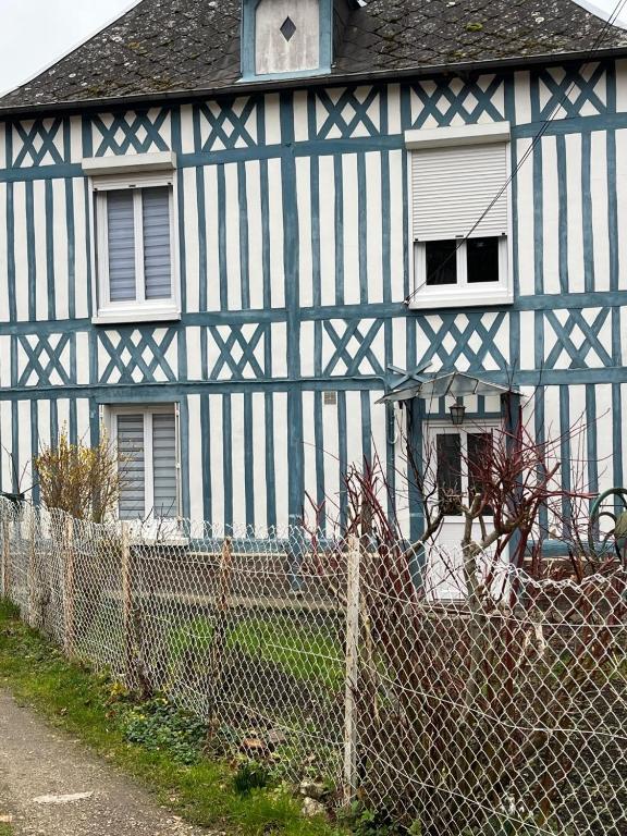 niebiesko-biały dom za płotem w obiekcie Gite les colombages w mieście Doudeville