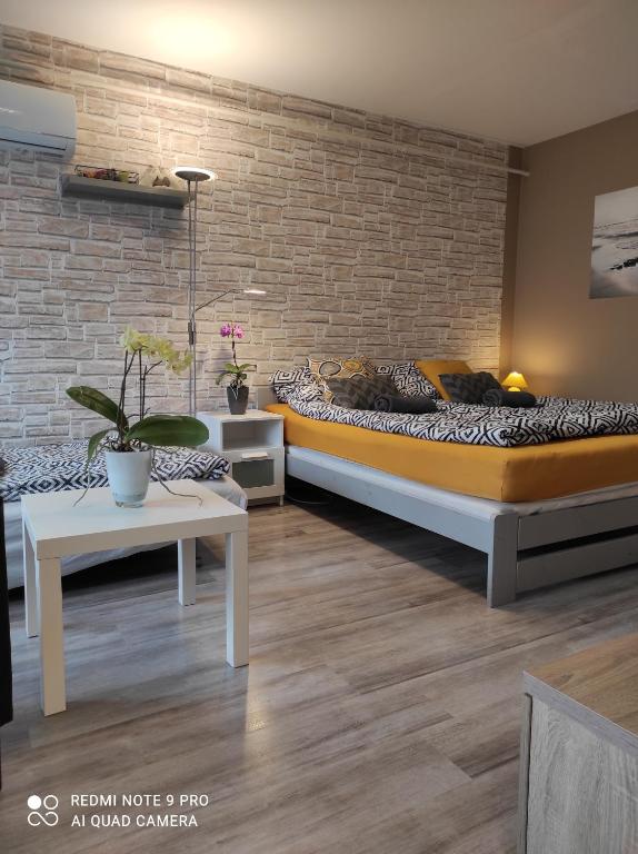 um quarto com 2 camas e uma parede de tijolos em Baross apartman em Kaposvár