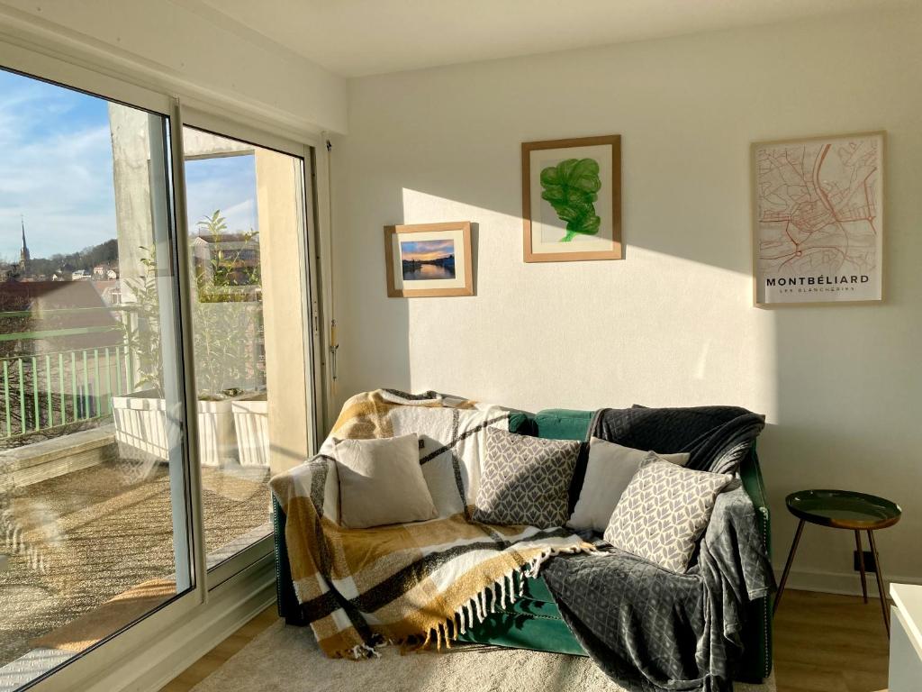 - un salon avec un canapé et une grande fenêtre dans l'établissement Appartement avec terrasse et parking gratuit accolé, à Montbéliard