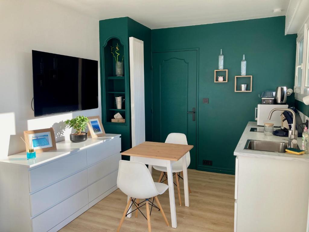 a kitchen with green walls and a table and chairs at Appartement avec terrasse et parking gratuit accolé in Montbéliard