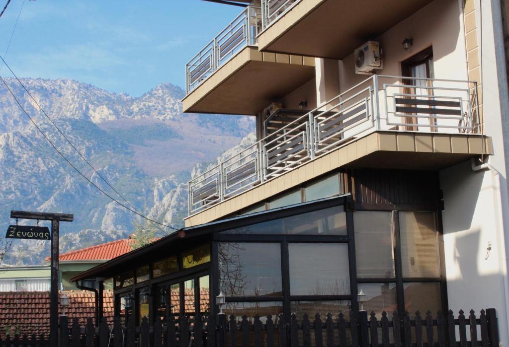 a building with a balcony with mountains in the background at Guesthouse Alexandros in Pýli