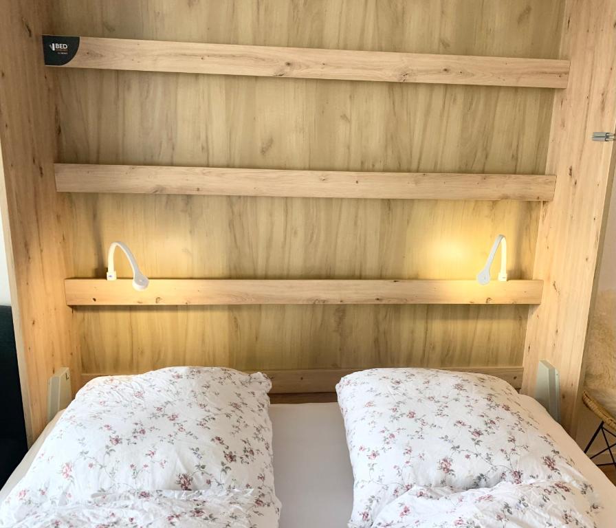 a bed with a wooden headboard with two pillows on it at FeWo Alpenwiese mit Hallenbad&Sauna in Missen-Wilhams