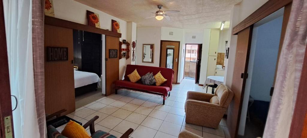 a living room with a red couch and a bedroom at See Uitsig 16 in Uvongo Beach