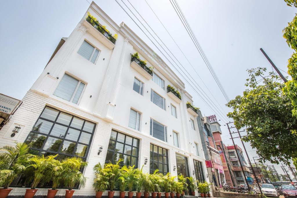 een wit gebouw met planten ervoor bij Hotel Asansol International in Āsansol