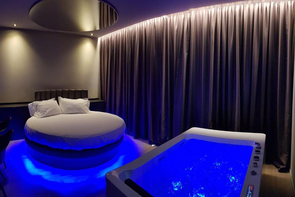 Leoni Hotel & Private Spa - LOVE HOTEL في شيتا سانت أنجيلو: غرفة بسرير وحوض استحمام مع ضوء ازرق