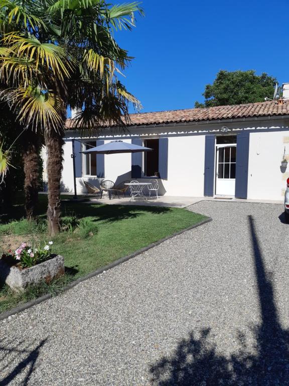 a white house with a palm tree and a patio at Bastida in Saint-Macaire