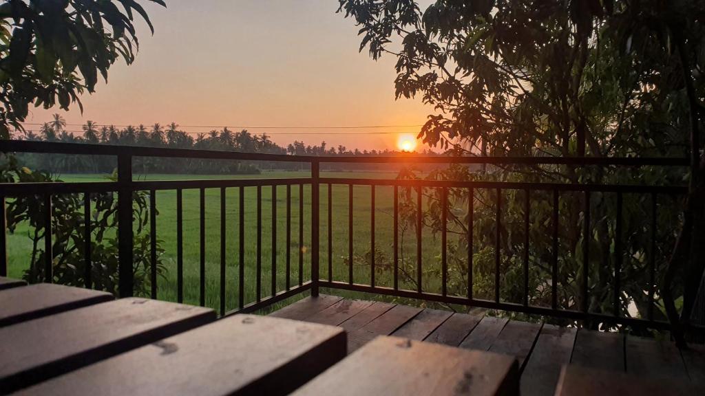 um pôr-do-sol sobre uma cerca com uma mesa de piquenique de madeira em Village Mango Resort Yala em Tissamaharama