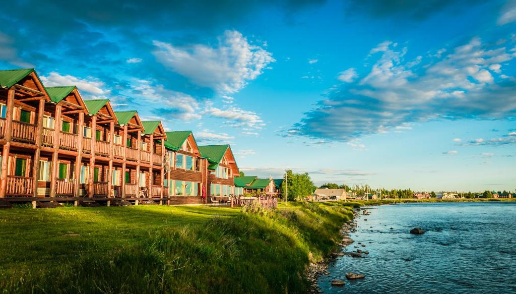 a row of wooden buildings next to a river at Angler's Lodge in Island Park