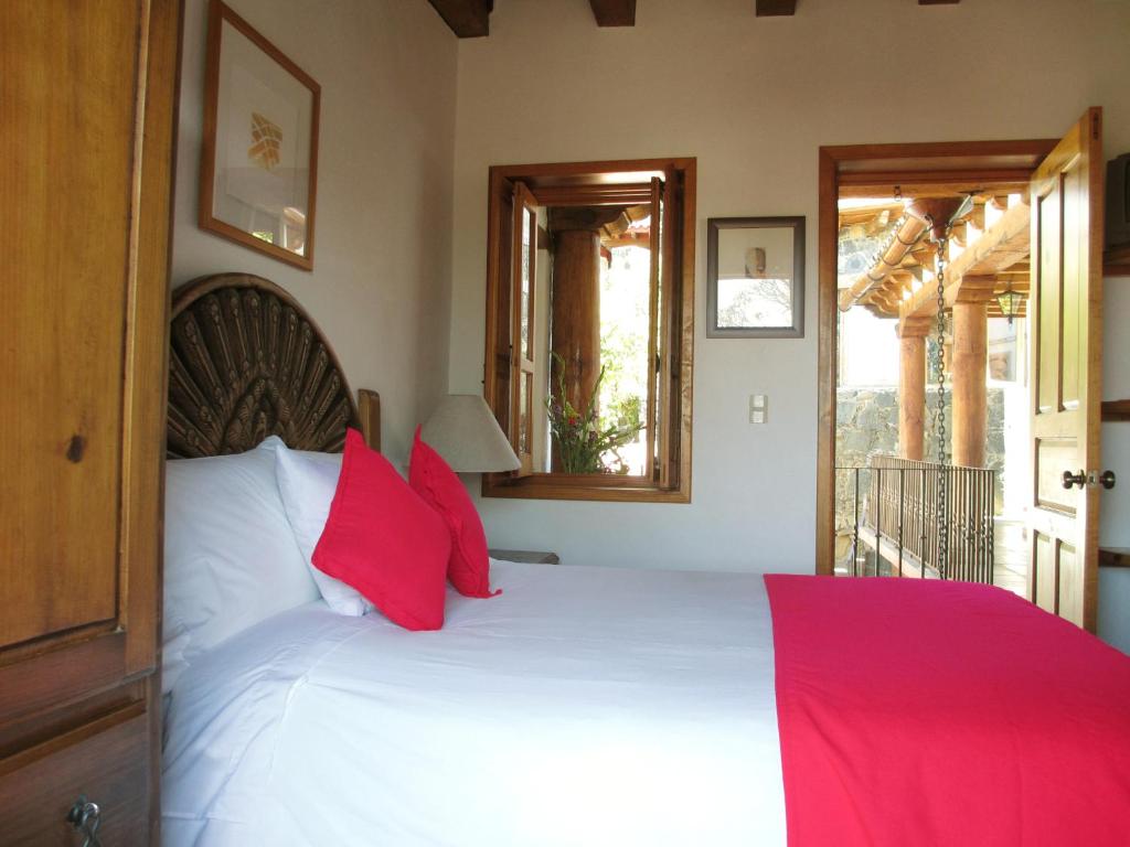 a bedroom with a large white bed with red pillows at Hotel Estancia de la Era B&B in Pátzcuaro