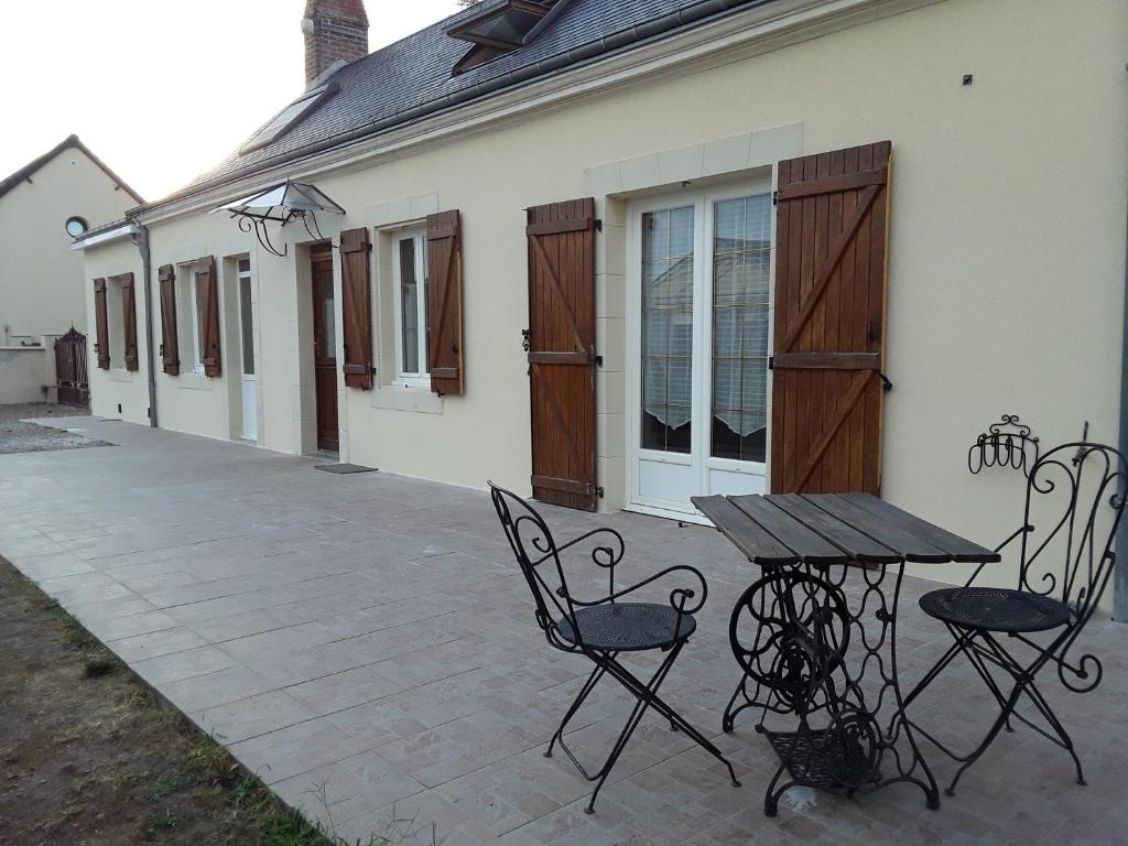 a patio with a table and chairs in front of a house at Chaleureuse fermette à proximité du circuit des 24h du MANS in Ruaudin