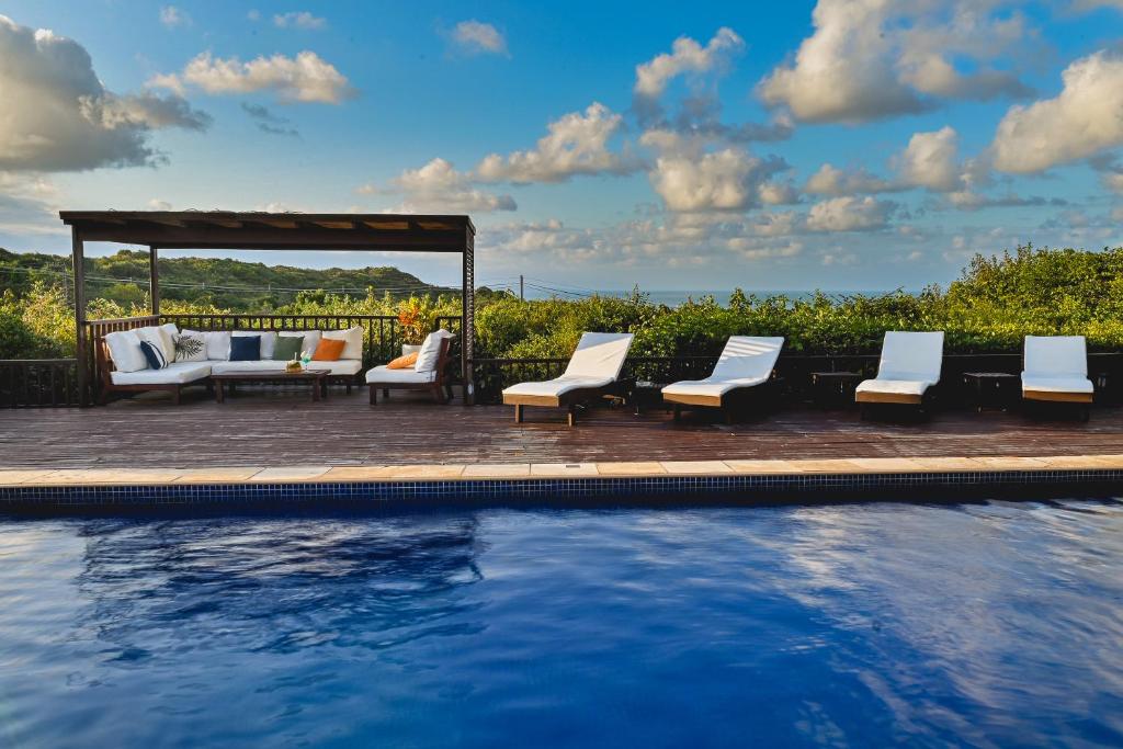 a swimming pool with chairs and a gazebo at Oka Da Mata in Pipa