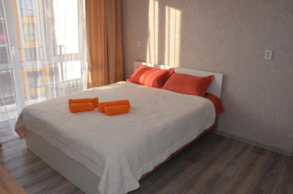a bedroom with a bed with orange pillows on it at Студия №1 LifeHouseAlmaty в ЖК Теремки-2 in Almaty