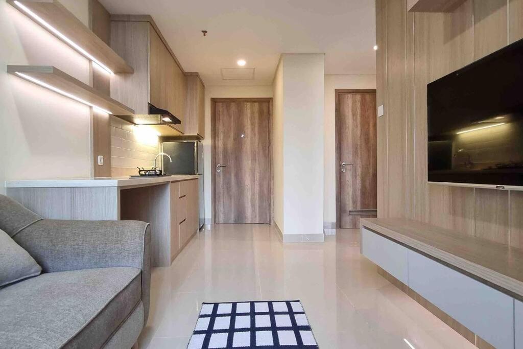 a living room with a couch and a flat screen tv at Apt Pejaten Park 1BR Khaki with SmartTv and Pool in Jakarta