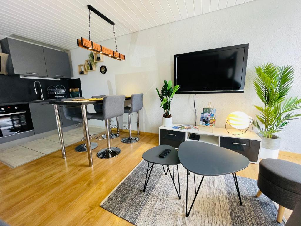 - un salon avec une table, des chaises et une télévision dans l'établissement Au Doubs Village, à Métabief