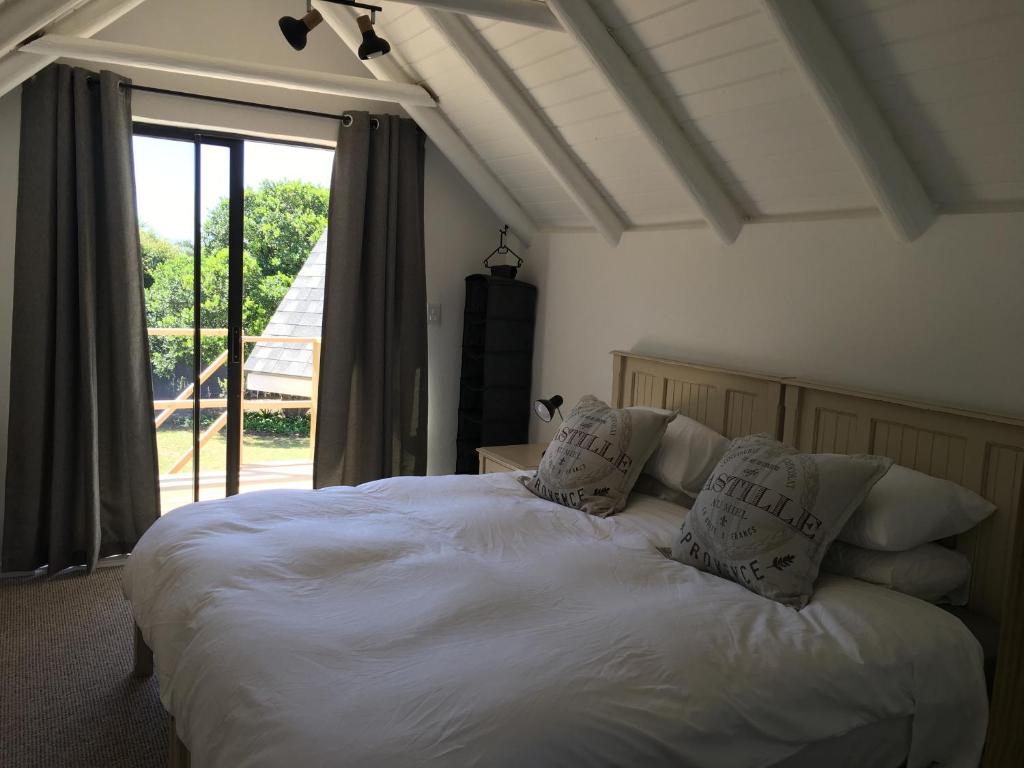 - une chambre avec un lit blanc avec des oreillers et une fenêtre dans l'établissement 47 on the Run, à St Francis Bay