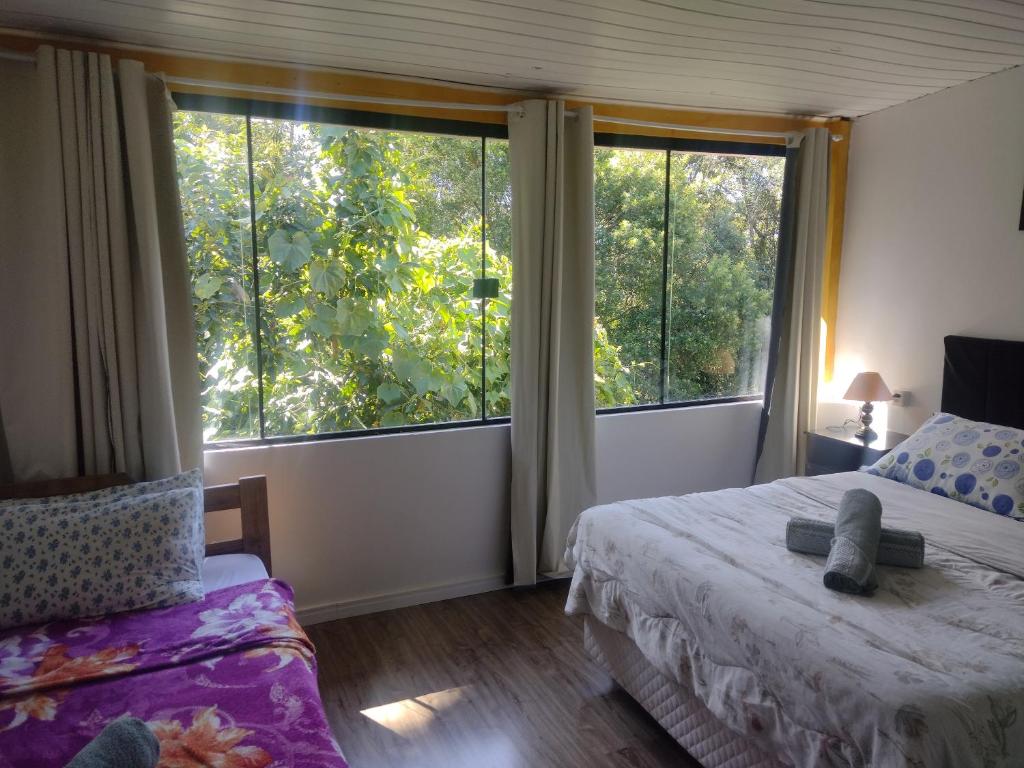 1 dormitorio con 2 camas y 2 ventanas grandes en Pousada Petry, en Gramado