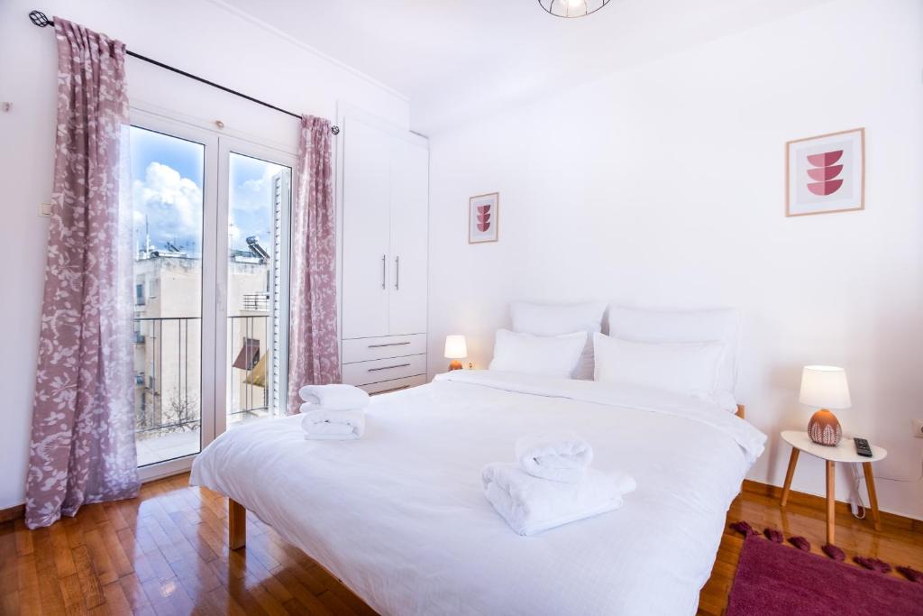biała sypialnia z dużym łóżkiem i oknem w obiekcie Loft Apt with Acropolis View w Atenach