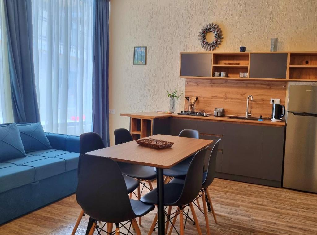 eine Küche und ein Wohnzimmer mit einem Tisch und einem blauen Sofa in der Unterkunft Greenfield Bakuriani in Bakuriani