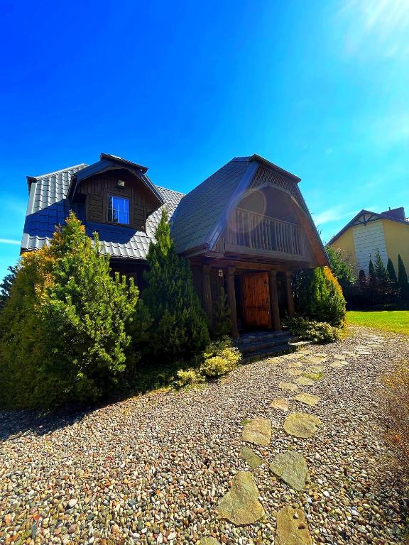 a house with a gambrel roof and a gravel driveway at Dom Karwia in Karwia