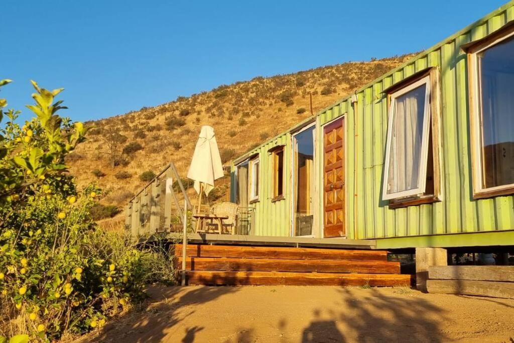 una casa verde con mesa y sombrilla en Altos de Curacavi, en Curacaví