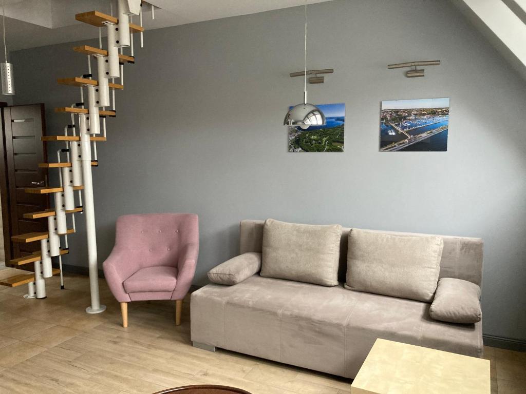 een woonkamer met een bank en een roze stoel bij Apartament Giżycko in Giżycko