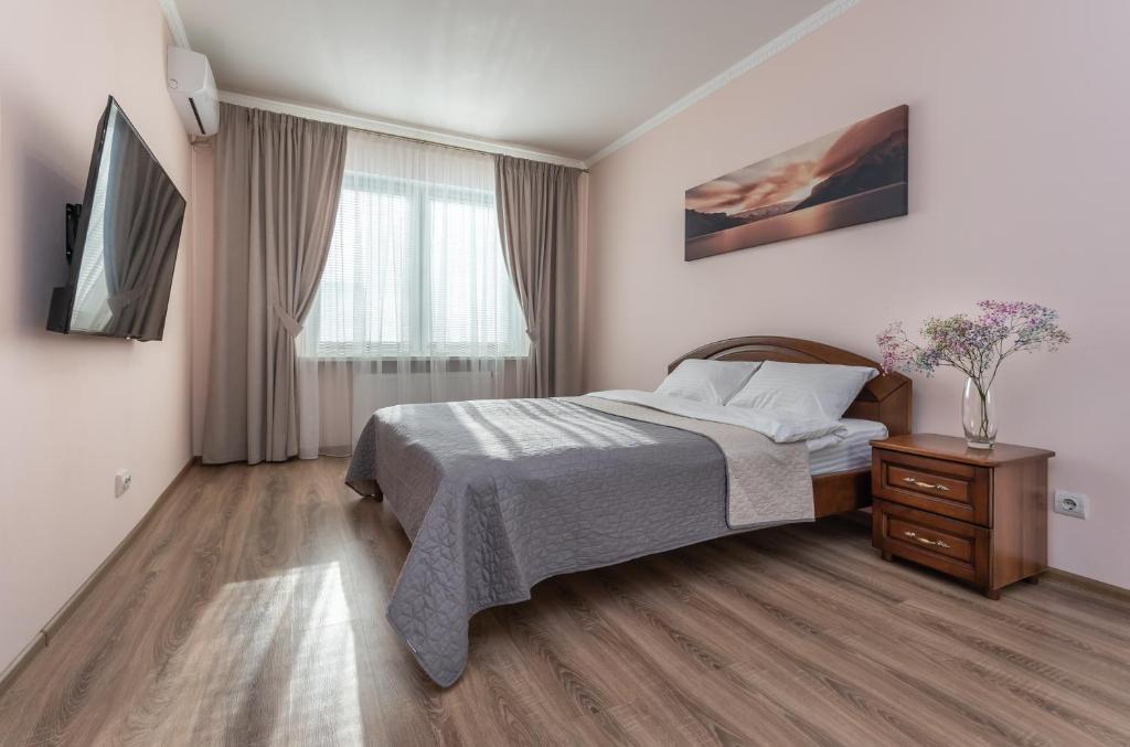 een slaapkamer met een bed, een dressoir en een televisie bij Осокорки Русовой 3 in Kiev