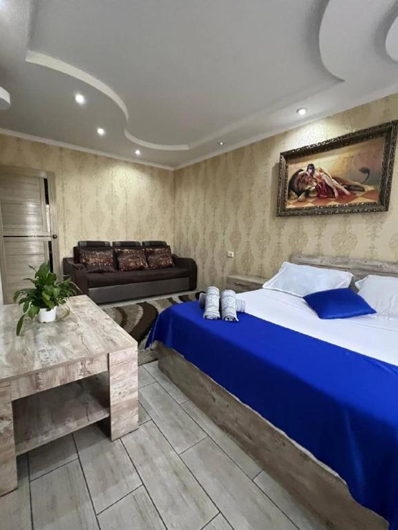 1 dormitorio con 1 cama azul y 1 sofá en LUX и комфорт, en Shymkent