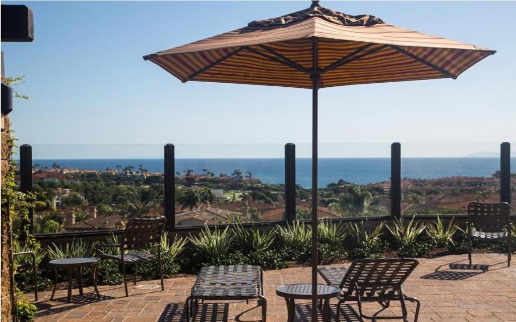 a patio with tables and chairs and an umbrella at Ritz Pointe Paradise! in Dana Point