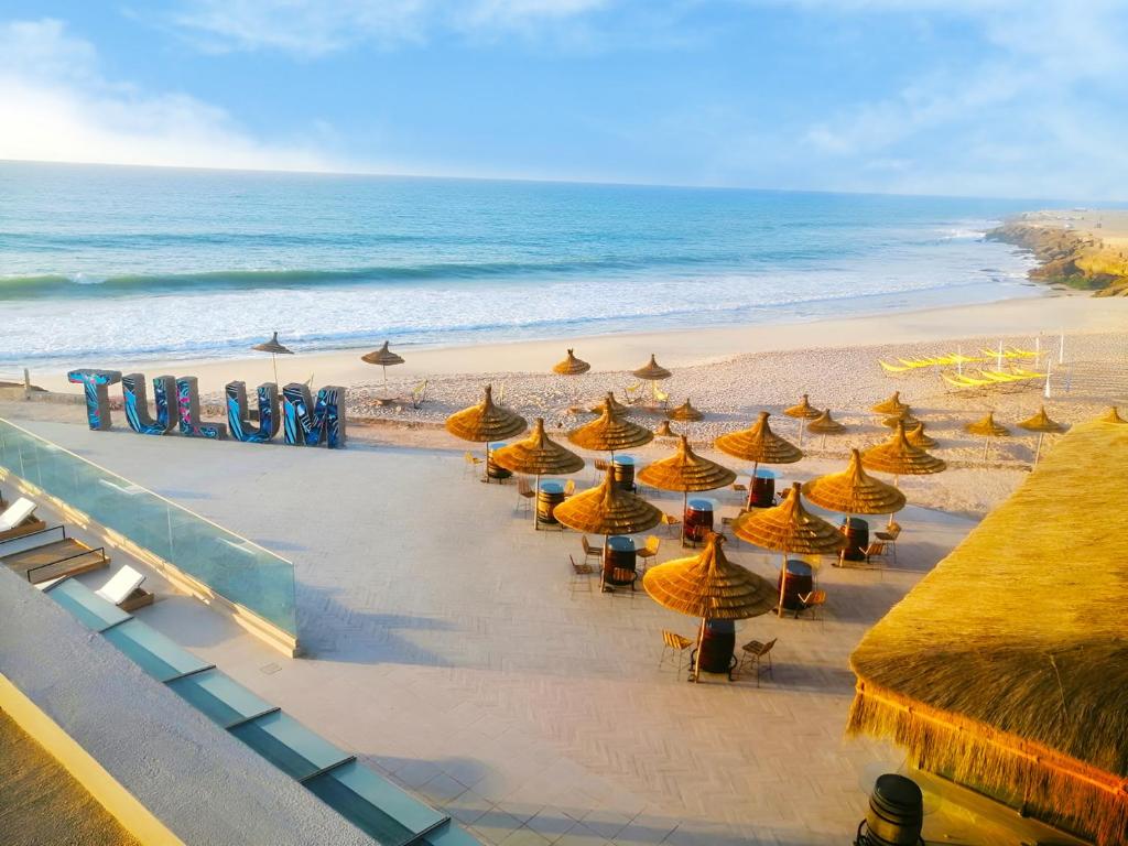 een strand met parasols en stoelen en de oceaan bij Tulum Beach Resort Dakhla in Dakhla