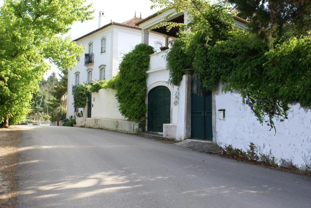 ein weißes Haus mit grüner Tür auf einer Straße in der Unterkunft Quinta de São Lourenço in São Lourenço do Bairro