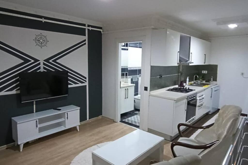 a kitchen with white cabinets and a tv in a room at Daire Beşiktaş Merkez in Istanbul