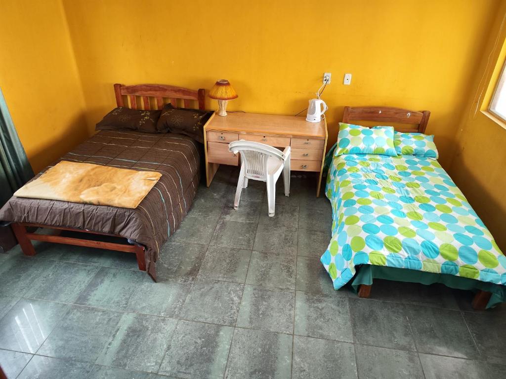 a bedroom with two beds and a desk and a table at Tapia house in Sucre